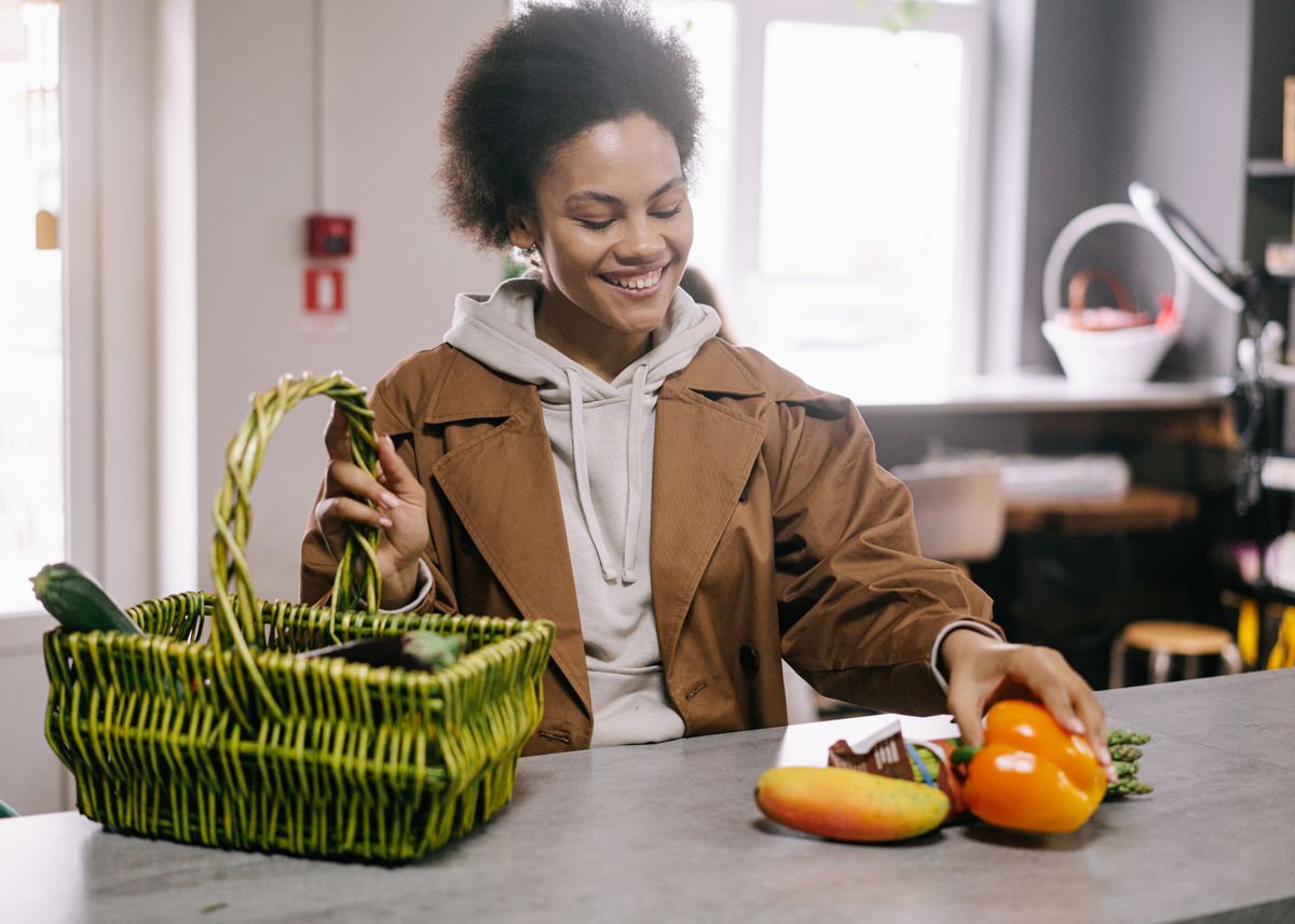 A happy customer with a shopping basket among the shelves of a convenience shop