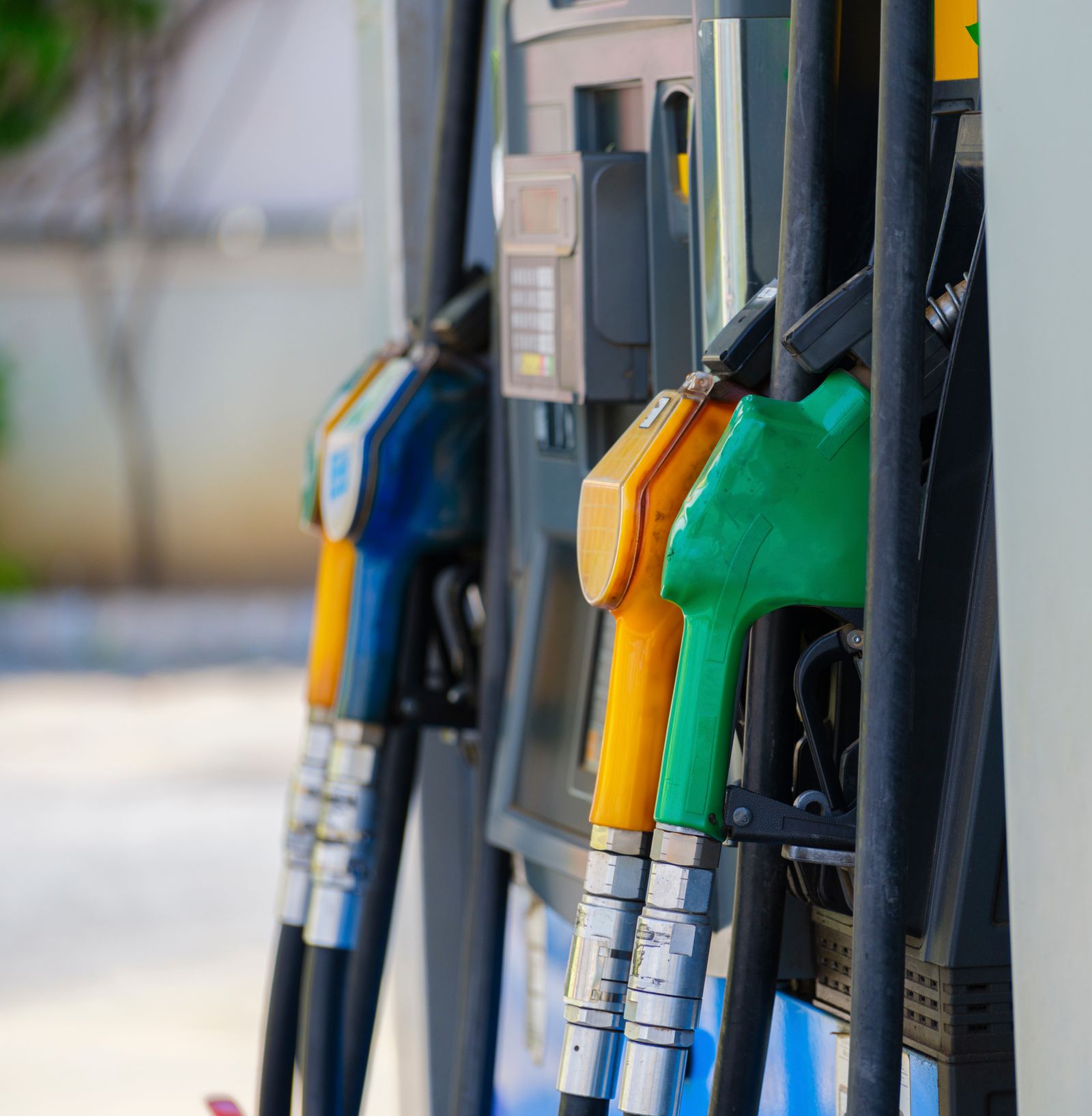 A row of coloured fuel pump nozzles on a forecourt dispenser